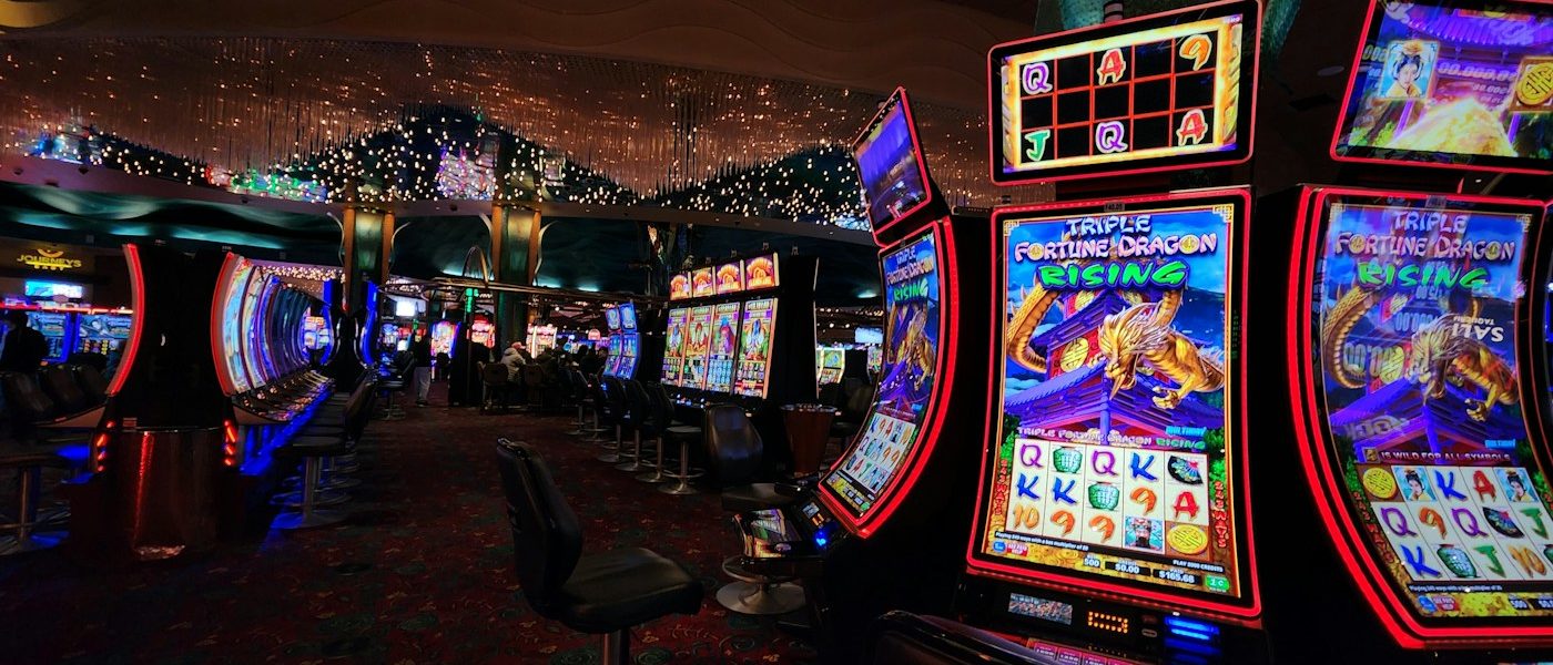 Row of glowing slot machines in a dimly lit casino, with neon lights and patterned carpet.